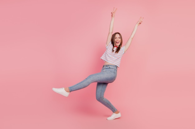 Portrait of carefree crazy funky lady dance show v-signs open mouth on pink background