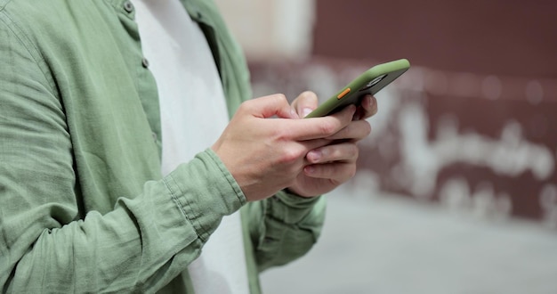 Portrait of casual man in glasses using smartphone on the street Handsom bearded man typing messages on phone outside Online messaging and browsing internet