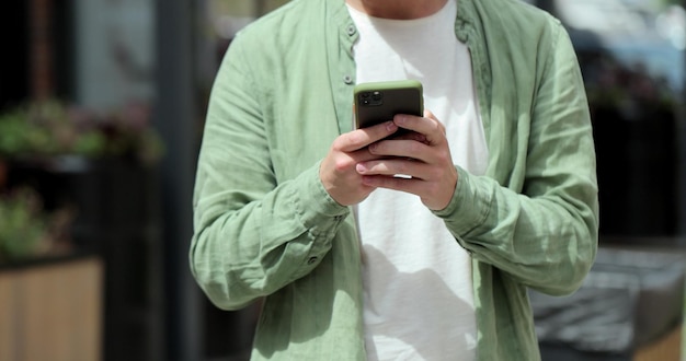 Portrait of casual man using smartphone outdoor Cheerful man typing messages on phone outside Online messaging and browsing internet