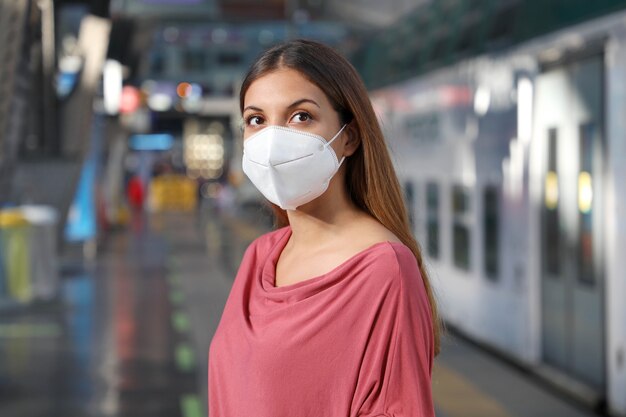 Portrait of casual woman waiting subway metro train with protective mask at underground station