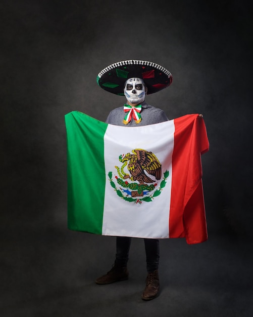 Portrait of catrin wearing charro hat and showing mexican flag Day of the dead