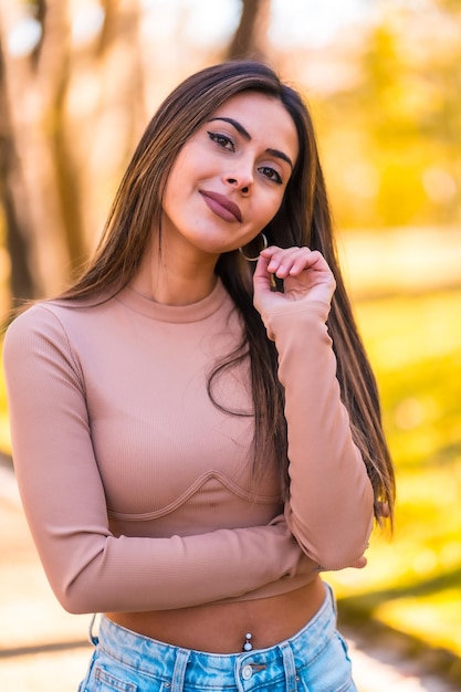 Portrait of a Caucasian model with a pink sweater and jeans walking in a park in autumn