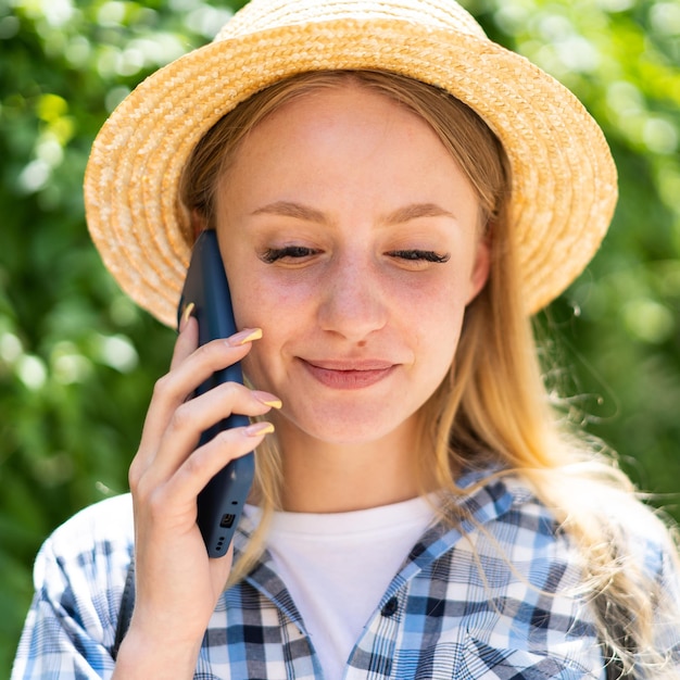 Portrait of a Caucasian tourist girl in a hat talking on a mobile phone while standing on the street young woman uses a cell phone for communication