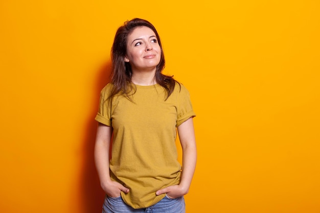 Portrait of caucasian woman standing in studio and smiling, looking at side. Young adult feeling happy and carefree over isolated background in front of camera. Joyful casual person