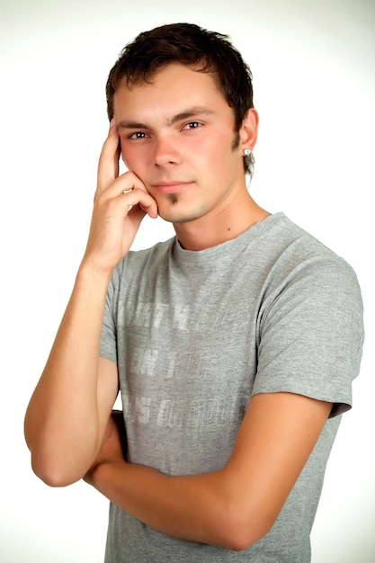 Portrait of a Caucasian young positive guy in a gray shirt and jeans