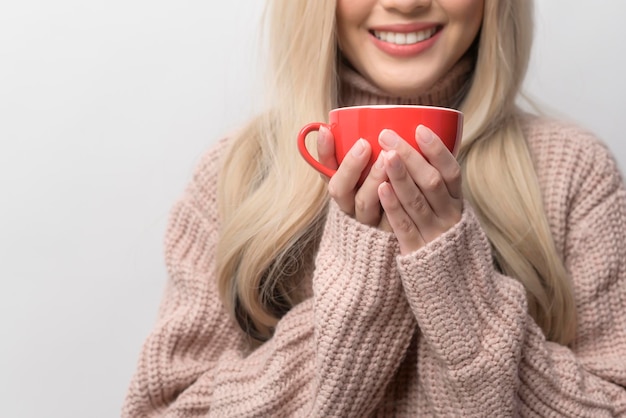 Portrait of Caucasian young woman wearing sweater drinking coffee over white background