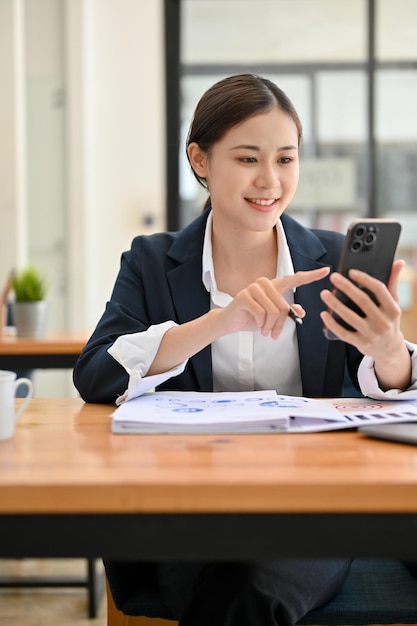 Portrait Charming Asian businesswoman using her smartphone to chat with her colleague