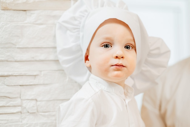 Portrait of a charming blue eyed two year old boy stained in flour while cooking homemade cakes