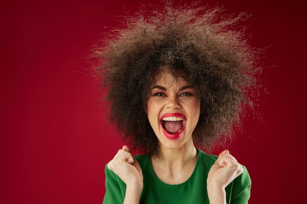 Portrait of a charming lady grimace afro hairstyle red lips fashion red background unaltered