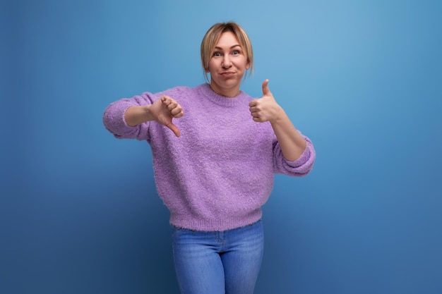 Portrait of charming pleasant blond young woman in purple sweater with grimace showing like and