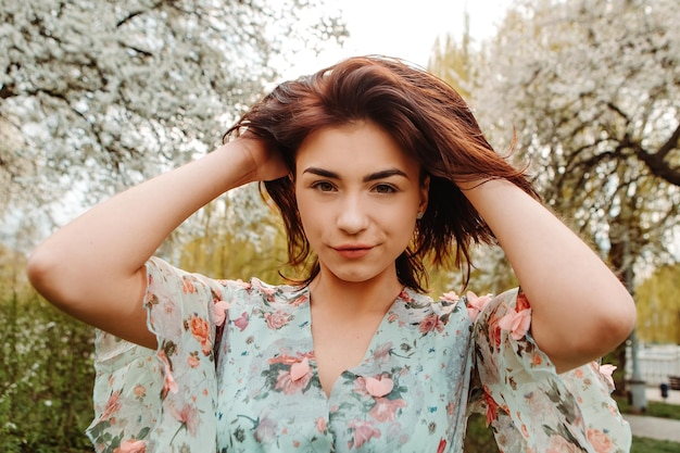 Portrait of charming woman posing near apple cherry tree blossoms blooming flowers in the garden