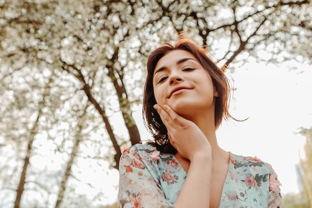 Portrait of charming woman posing near apple cherry tree blossoms blooming flowers in the garden