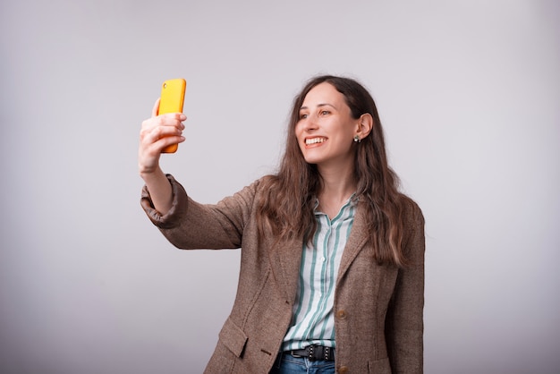 Portrait of charming young business woman taking selfie with smartphone.