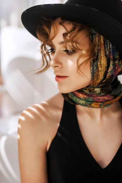 Photo portrait of a charming young woman in black hat with shadows light beautiful golden make up