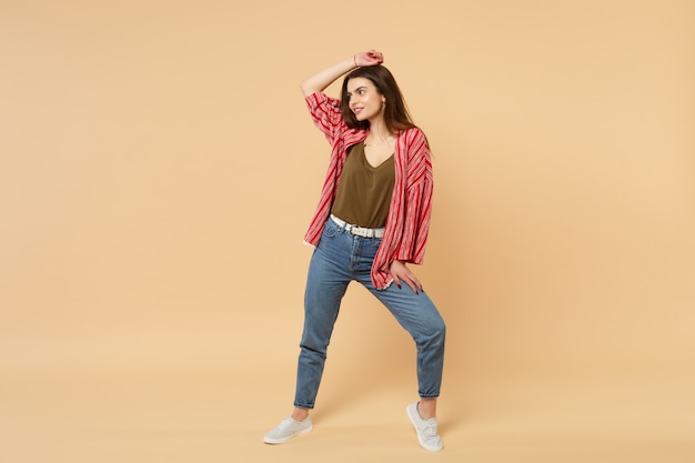 Portrait of charming young woman in casual clothes looking aside putting hand on head isolated on pastel beige wall background in studio. People sincere emotions lifestyle concept. Mock up copy space.