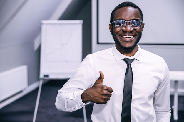 Portrait of cheerful african american manager looking at camera and holding thumbs up