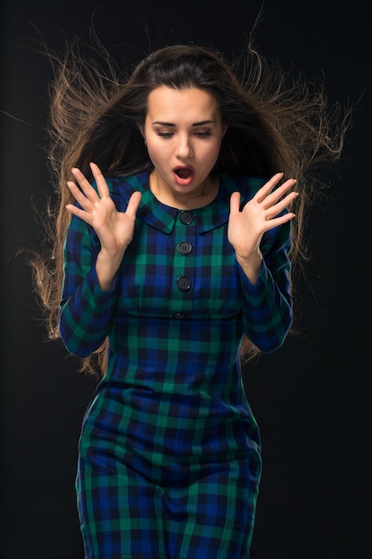 Portrait of cheerful attractive modern woman with long hair expressing emotions while standing over ...