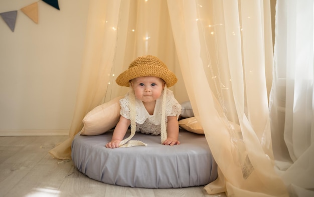 Portrait of a cheerful baby girl sitting on a mattress under a canopy and crawling