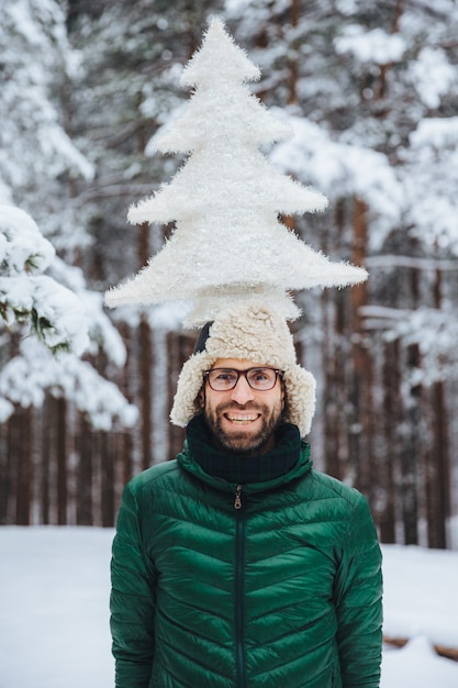 Portrait of cheerful bearded man has fun alone in winter forest