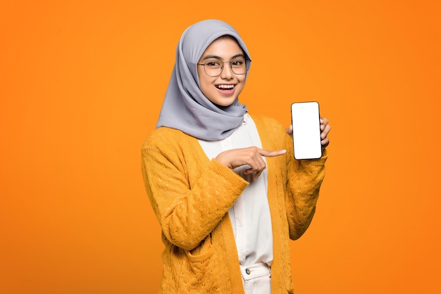 Portrait of cheerful beautiful Asian woman showing blank screen on smartphone