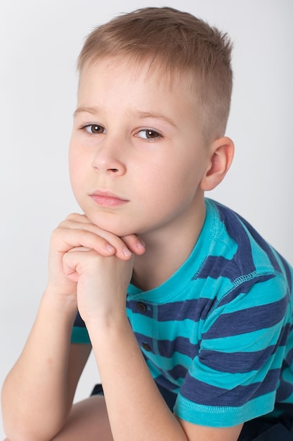 Portrait of cheerful boy with good idea isolated over blue background 10 year old kid pointing finger up Child points by finger upward Cheerful boy shows something