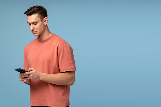 Portrait of cheerful brunette man in tshirt using cellphone and smiling