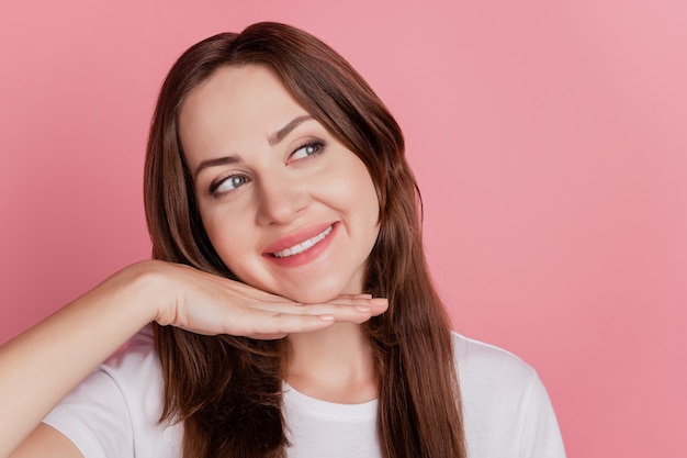 Portrait of cheerful dreamy creative girl hand chin look blank space on pink background