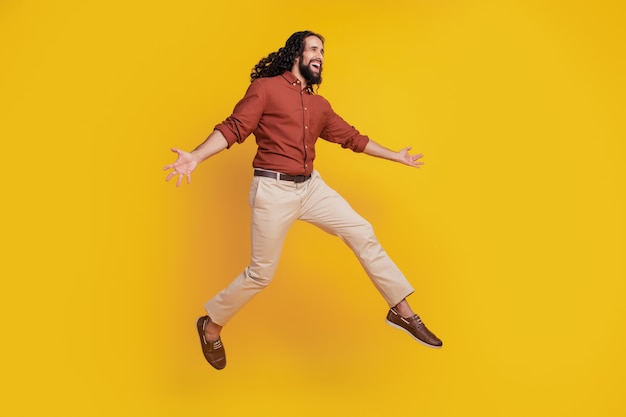 Portrait of cheerful funky guy jump enjoy have fun on yellow background