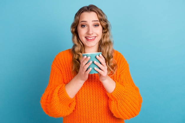 Portrait of cheerful funny young woman hold cup of coffee tea isolated on blue color background studio