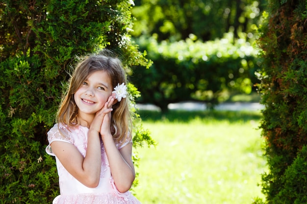 Portrait of a cheerful girl in a lush pink dress in the park.