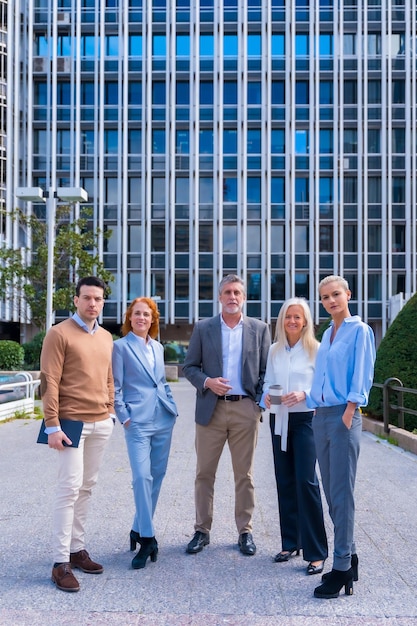 Portrait of cheerful group of coworkers walking outdoors in a corporate office area