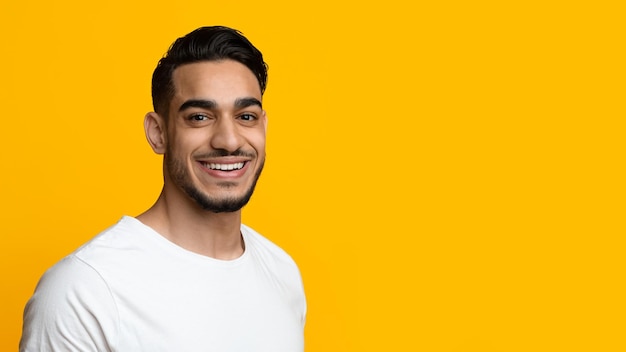 Portrait of cheerful handsome middle eastern young man on yellow