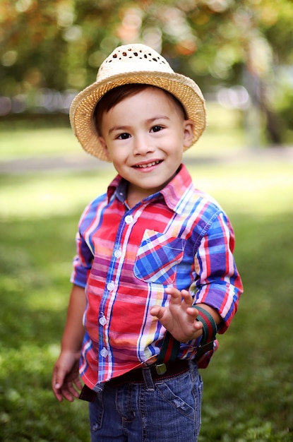 Portrait of a cheerful happy child in a straw hat playing in a summer Park .