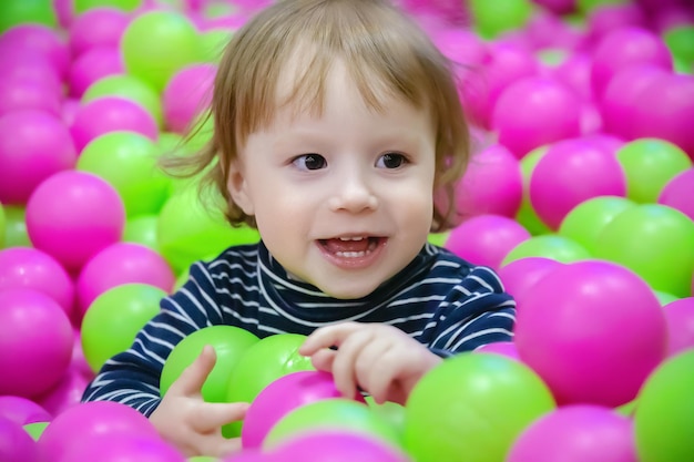 Portrait of cheerful kid playing with colorful balls children's day concept closeup