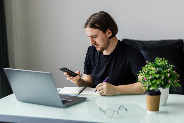 Portrait of cheerful man using smart phone at home office