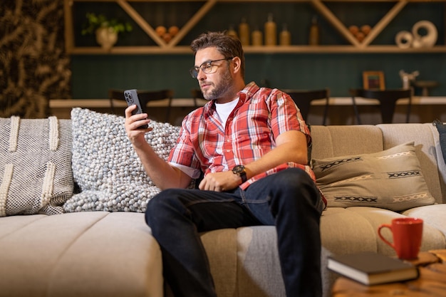 Portrait of a cheerful man with smart phone at home guy using phone at home middle eastern mature ma