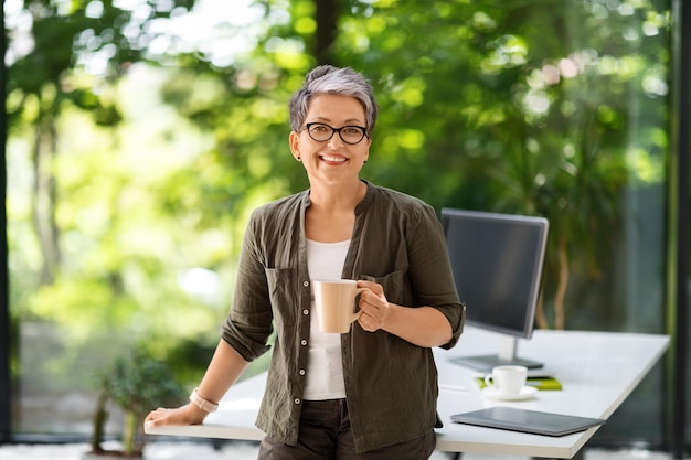 Portrait of cheerful mature woman drinking coffee at office