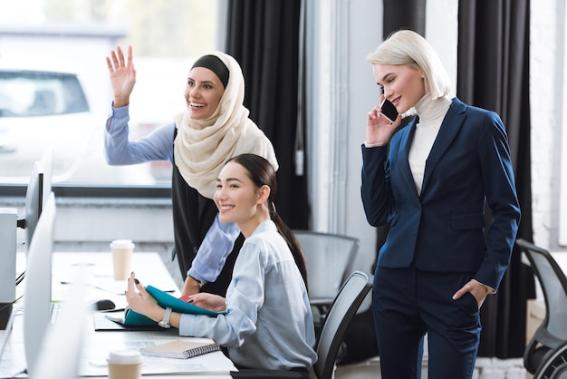 portrait of cheerful multicultural businesswomen at workplace in office