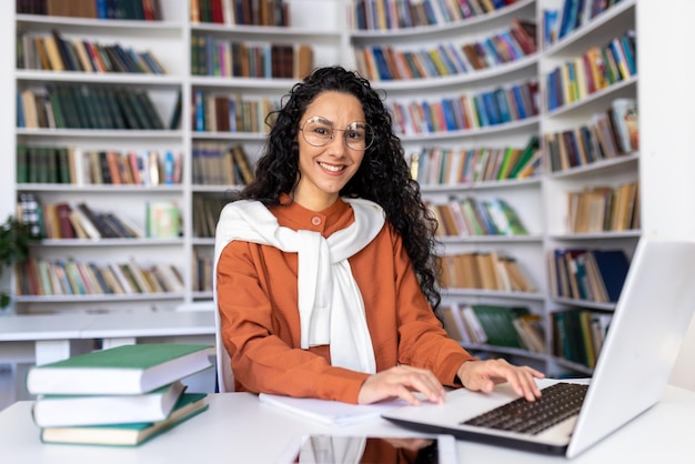 Portrait of cheerful smiling girl student woman looking at camera sitting studying with laptop