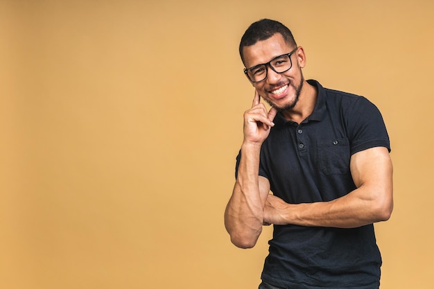 Portrait of a cheerful smiling young african american black man standing isolated over beige background