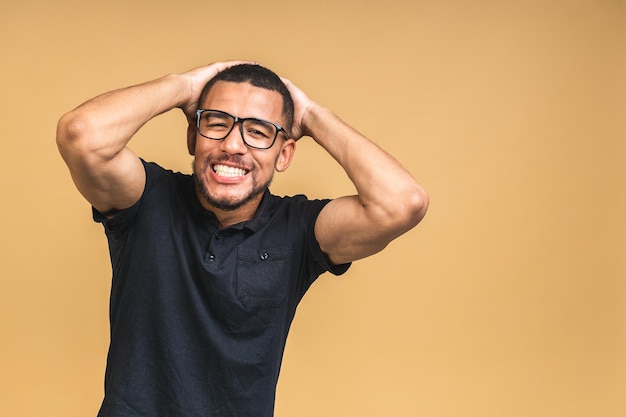 Portrait of a cheerful smiling young african american black man standing isolated over beige background