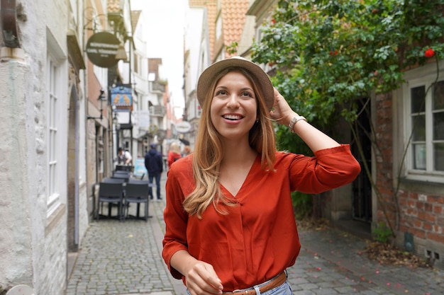 Portrait of cheerful traveler woman walking in Schnoor neighborhood Bremen Germany