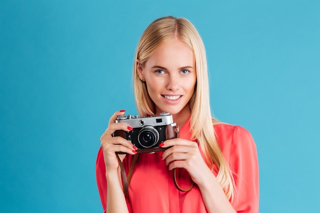 Portrait of a cheerful woman making photo on front over blue wall