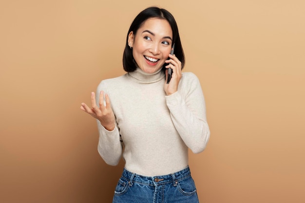 Portrait of cheerful woman talking with friend on cell phone