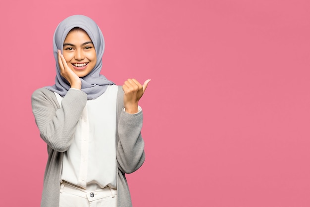 Portrait of cheerful young Asian woman pointing to copy space