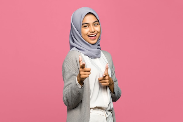 Portrait of cheerful young Asian woman pointing fingers to camera with smiling face