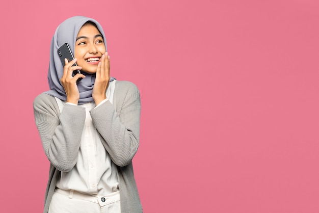 Portrait of cheerful young Asian woman talking with friends in mobile phone