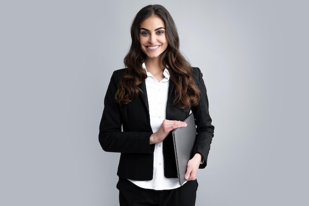 Portrait of cheerful young casual girl standing isolated over gray background using laptop computer