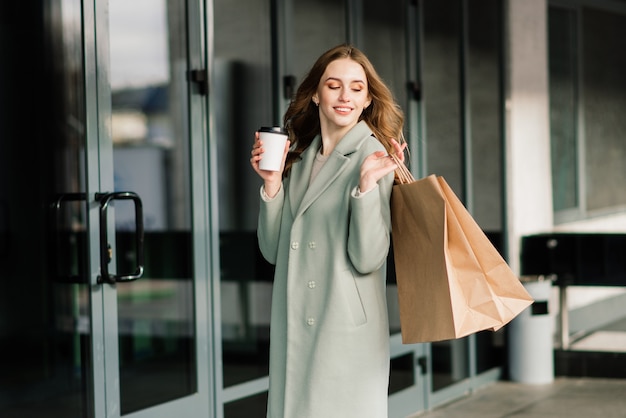 Portrait of a cheerful young lady holding shopping bags outdoor