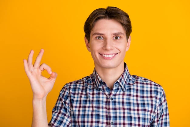 Portrait of cheerful young man showing okay gesture isolated on bright shine color background